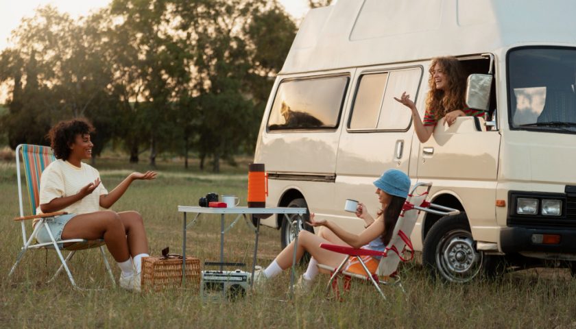 Des personnes assises autour d'une table de camping devant un van aménagé