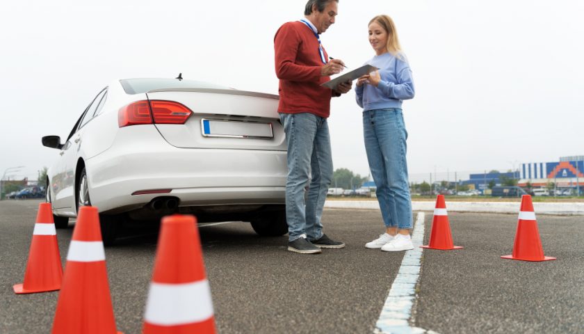 un inspecteur de permis avec une élève près d'une voiture