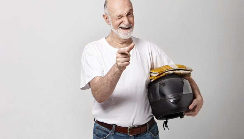 un homme agé tenant un casque de moto