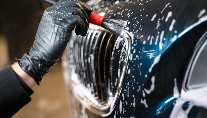 une personne appliquant de la colle sur une voiture pour réaliser un covering